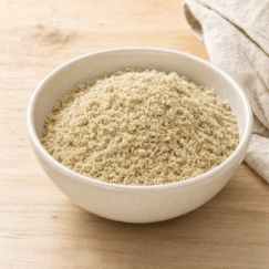 A bowl of finely ground pumpkin seed meal on a wood table