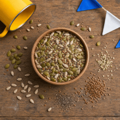 Overhead flatlay of pumpkin seeds, sunflower kernels, chia, and flax with a yellow camp mug
