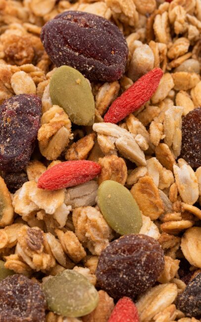 A close-up of granola with rolled oats, pumpkin seeds, dried cranberries, goji berries, and raisins